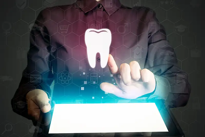 Glowing tooth floating above tablet device Glowing tooth floating above tablet device