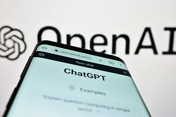 ChatGPT on a phone in front of OpenAI logo in background