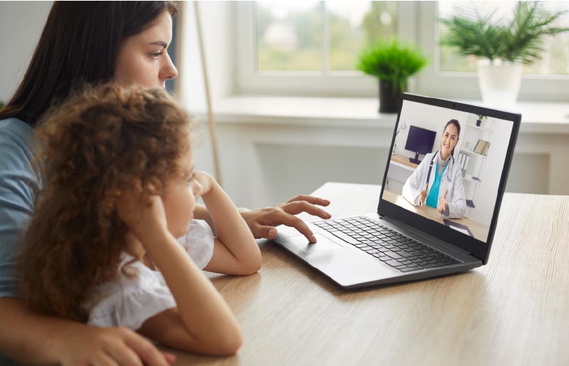Parent and child talking with dentist using tele-health